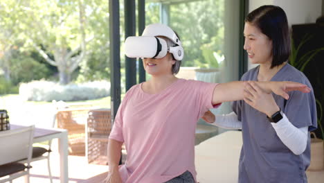 using vr headset, senior asian woman doing physical therapy with therapist at home