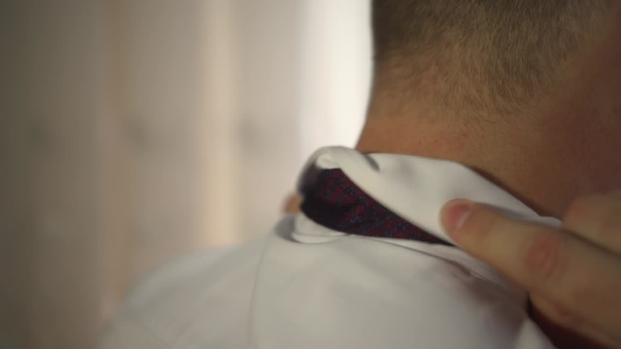 el hombre ajusta el cuello blanco y la corbata 01
