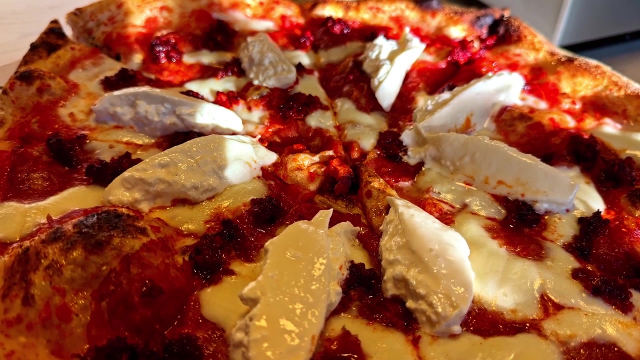 Una pizza appena sfornata è guarnita con formaggio cremoso e saporita salsa di pomodoro - Primo piano