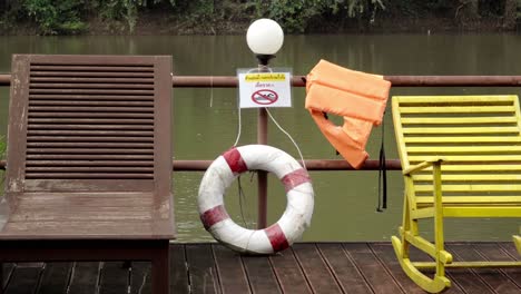 a tilt reveal shot of two loungers on the deck of a houseboat on the khwae river, people are advised not to swim and safety equipment is provided in the case of an emergency in kanchanaburi, thailand