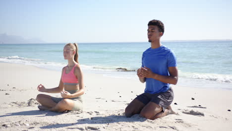 a man and woman are meditating on a sunny beach with clear skies