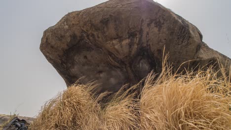 ein vergrößerter zeitraffer eines großen granitfelsens in afrika, der durch das gras weht