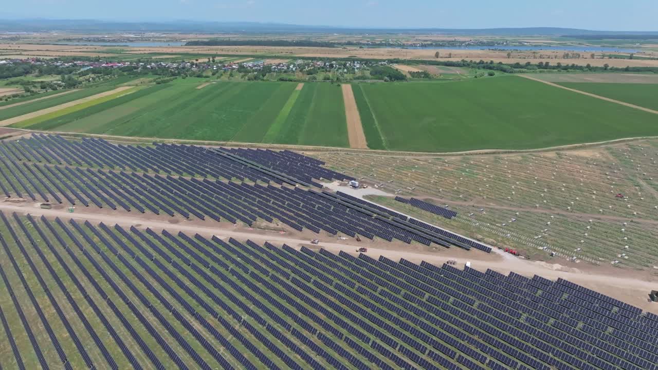 Aerial view of solar farm with vast green fields, clear sky and horizon