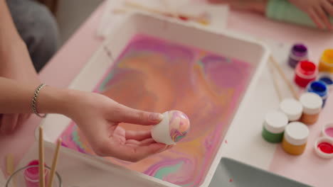 lady shows easter egg with abstract pattern of ebru art