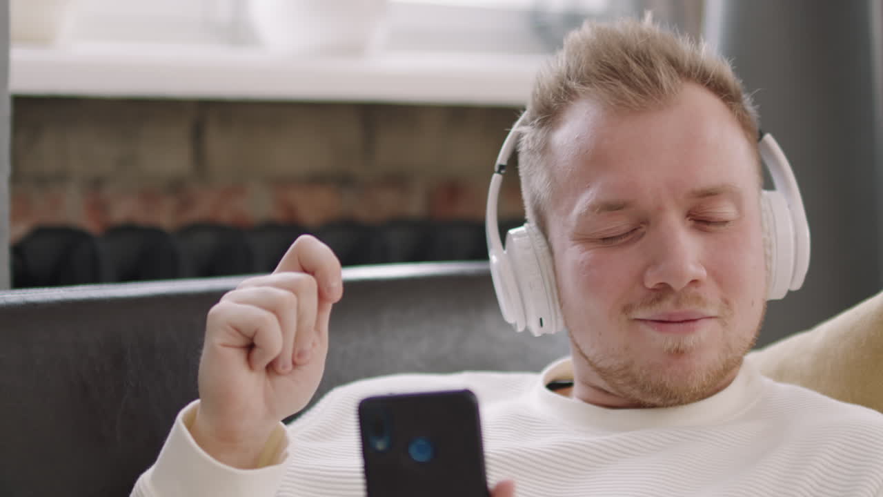 Cheerful Young Man in Headphones Enjoying Music
