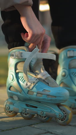 una persona sentada en un parque, atando las correas de su segunda patineta mientras ya lleva la primera. momentos de preparación antes de participar en una actividad de patineta