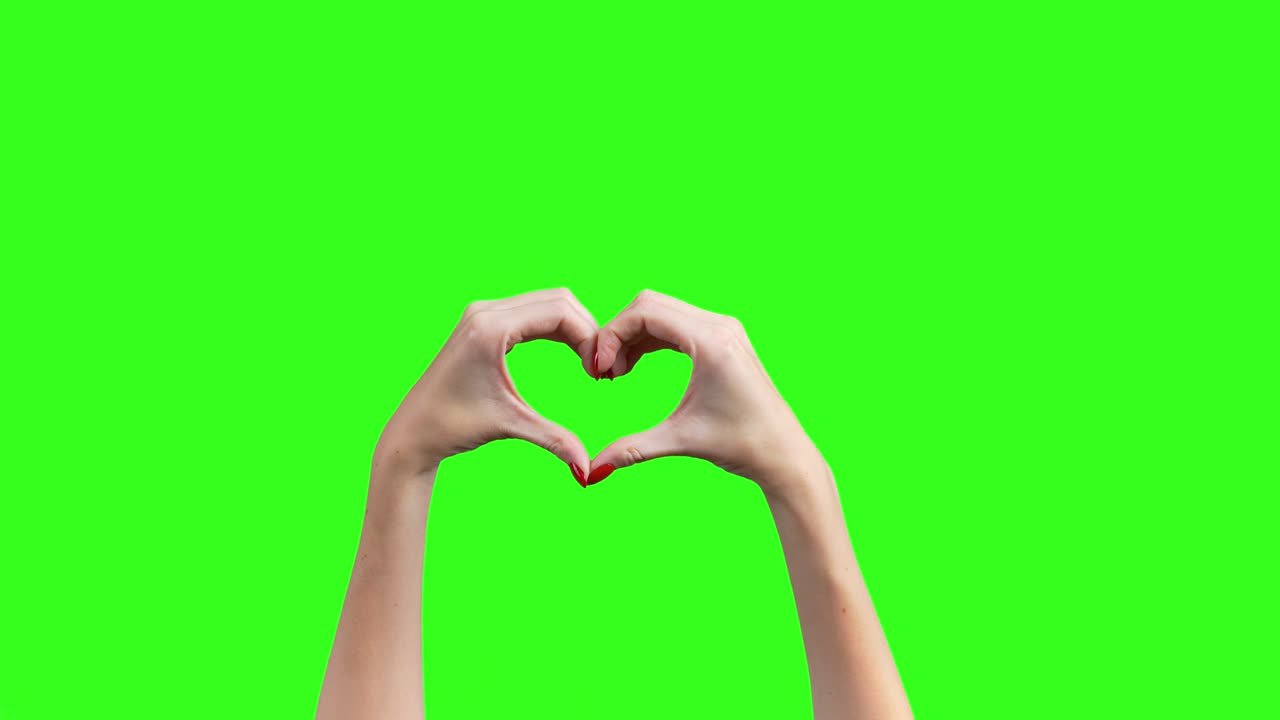 disparo de manos femeninas que muestran el gesto del corazón en fondo verde