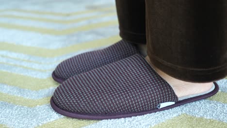 person wearing brown slippers on a carpet