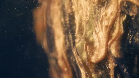 las partículas de tinta dorada fluyen en el agua como un caos colorido en el fondo negro