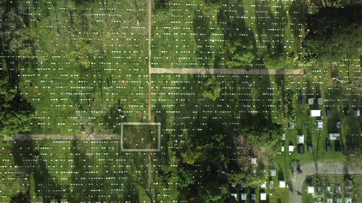 Top down drone shot of cemetery path and road with cars