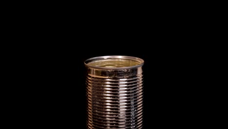 multiple open tin cans filled with longan fruit are arranged on a black background as a longan splashes into one can, captured with dramatic lighting