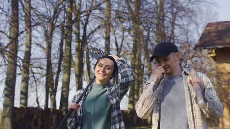 Close-up-view-of-caucasian-holding-hands-and-carrying-rakes-while-walking-throught-the-countryside