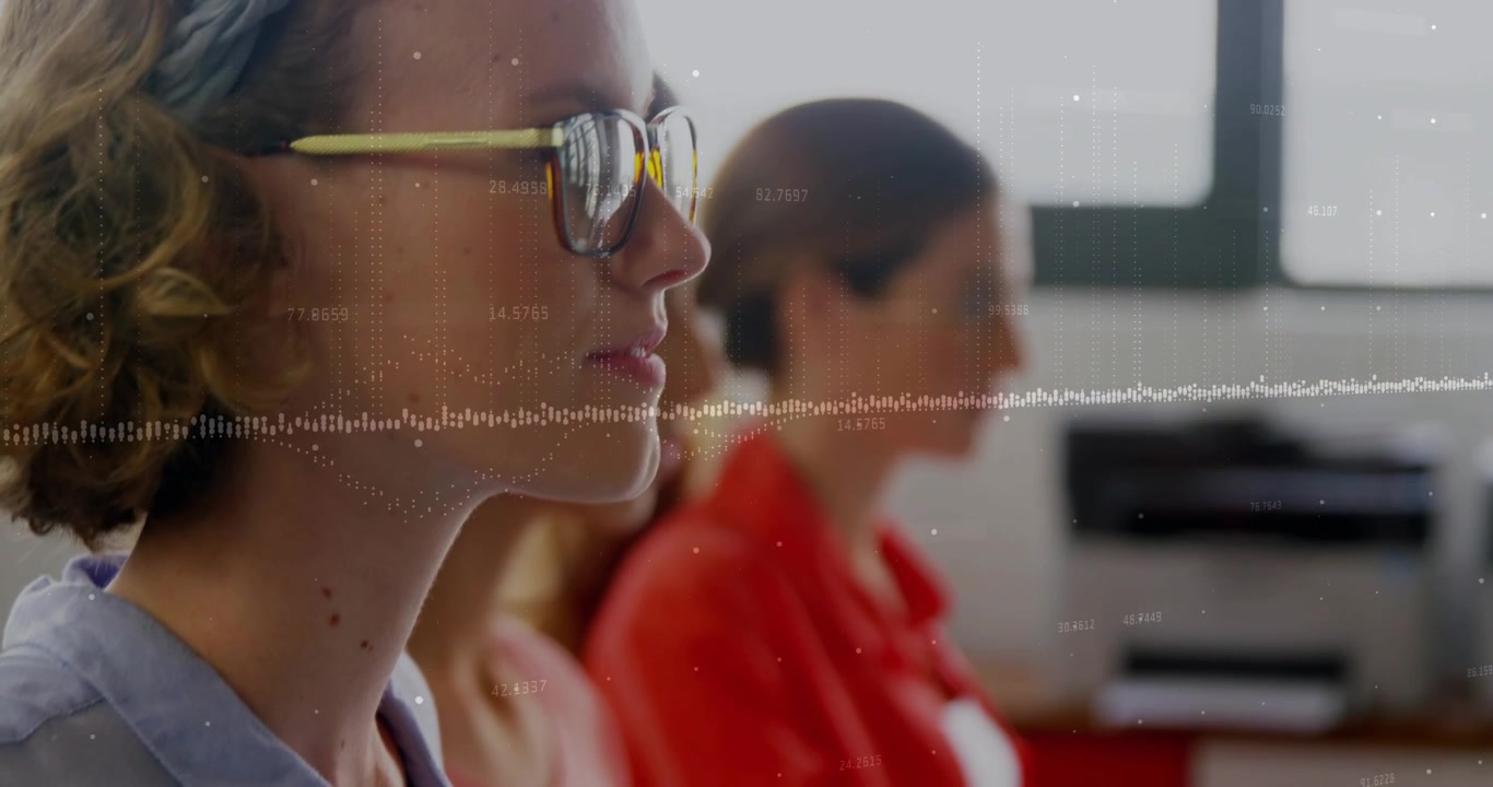 Leftmost woman typing on white keyboard in lab, waveform guiding peers toward offscreen presenter