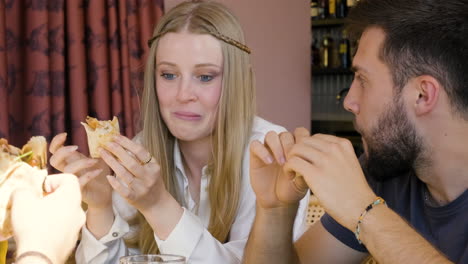 Happy-Friends-Eating-Pizza-And-Talking-At-Restaurant