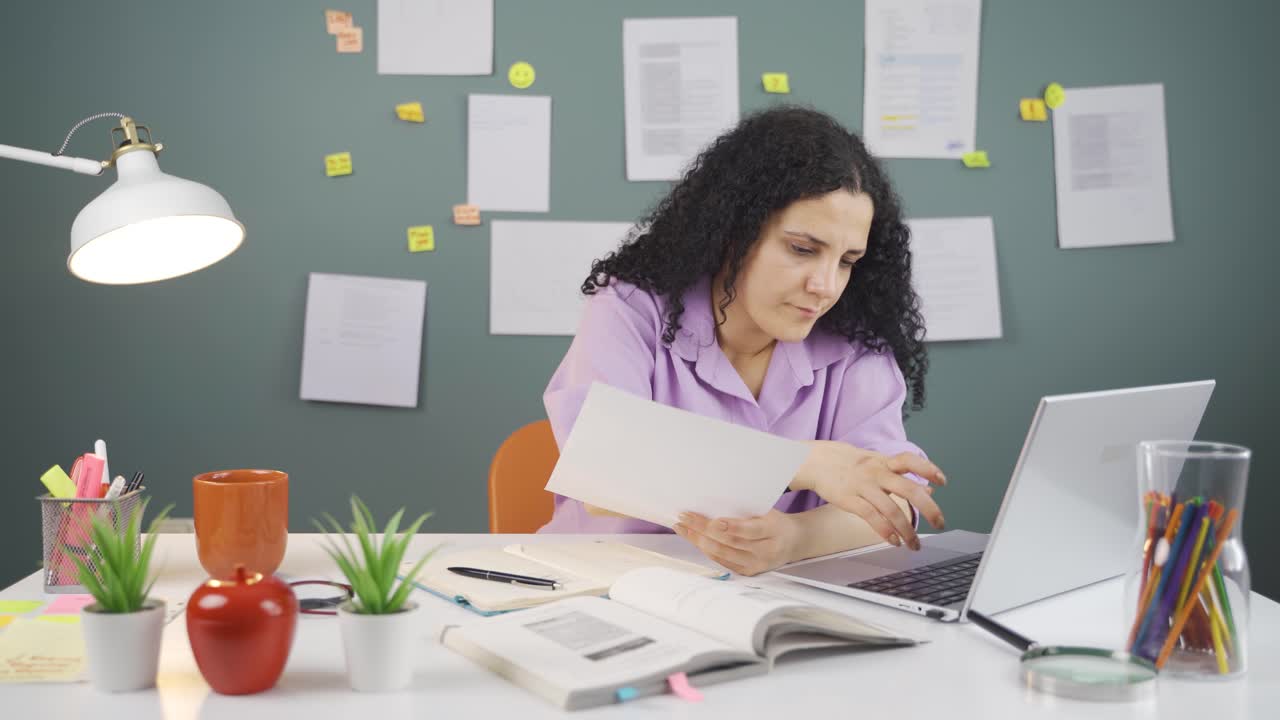 estudiante trabajando entre el papel y la computadora portátil.