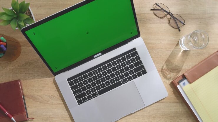 Laptop auf Holzschreibtisch mit Büromaterialien.