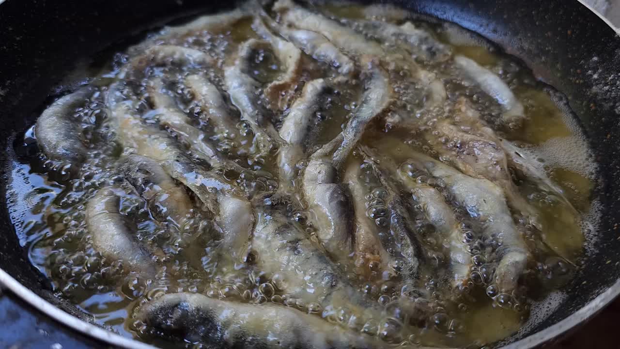sardinas recién capturadas por pescadores con botes y redes que pescan en las costas del mar mediterráneo están siendo fritas en una sartén para un delicioso almuerzo