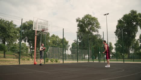 Dos-Jugadores-De-Baloncesto-Masculino-Entrenando-Juntos-En-Una-Cancha-De-Baloncesto-Al-Aire-Libre-1