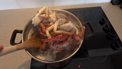 stirring crab legs in a pot on a stove