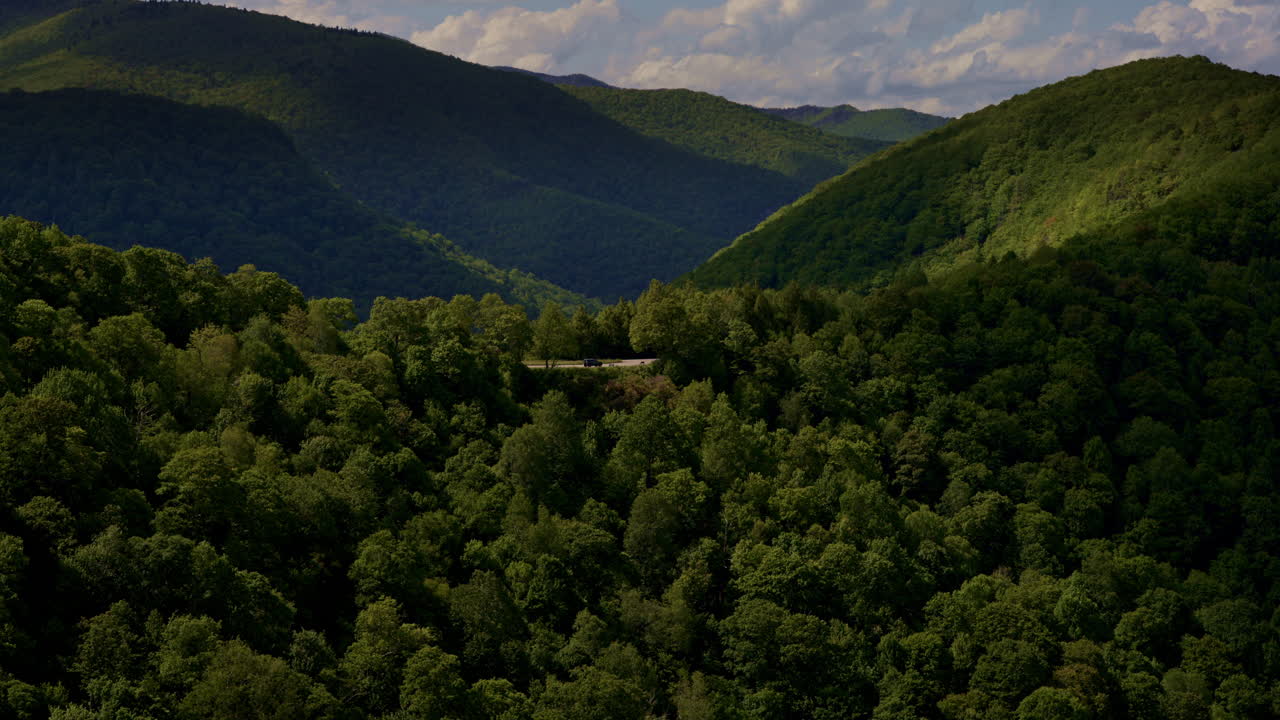 Graceful, cinematic drone shot gliding over the Blue Ridge Parkway as a lone truck drives along the winding road
