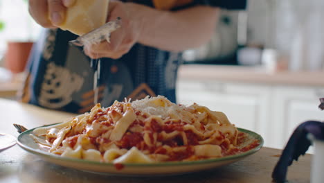 grating cheese over freshly prepared homemade pasta with sauce