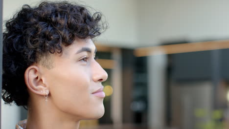 close-up of young man with curly hair and earrings looking thoughtfully, copy space