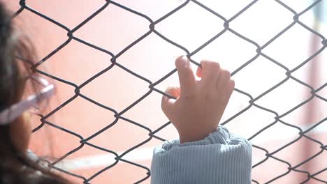 금속 울타리를 고 손을 는 아이
