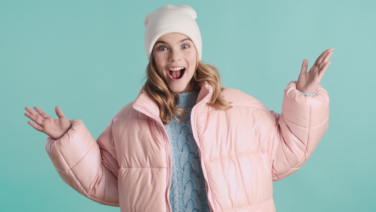 카메라 앞에 겨울 옷을 입은 쾌활한 십대 백인 소녀.