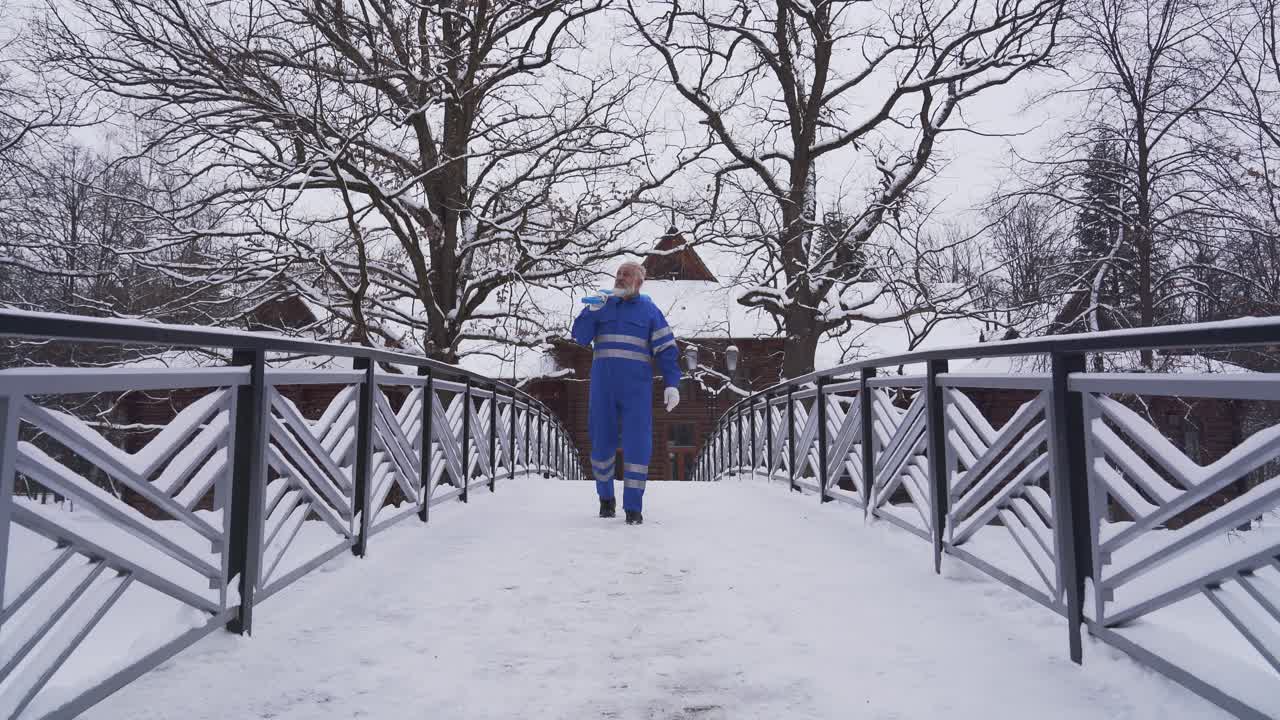 Old cleaner walking with shovel on shoulder.