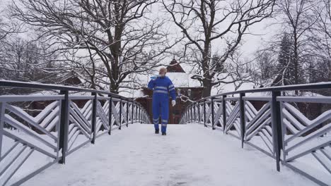 Old cleaner walking with shovel on shoulder.