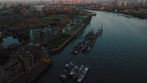 harbour with moored ships in city landscape in london at sunset