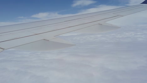 Close-up-of-airplane-wing-in-the-air-with-clouds