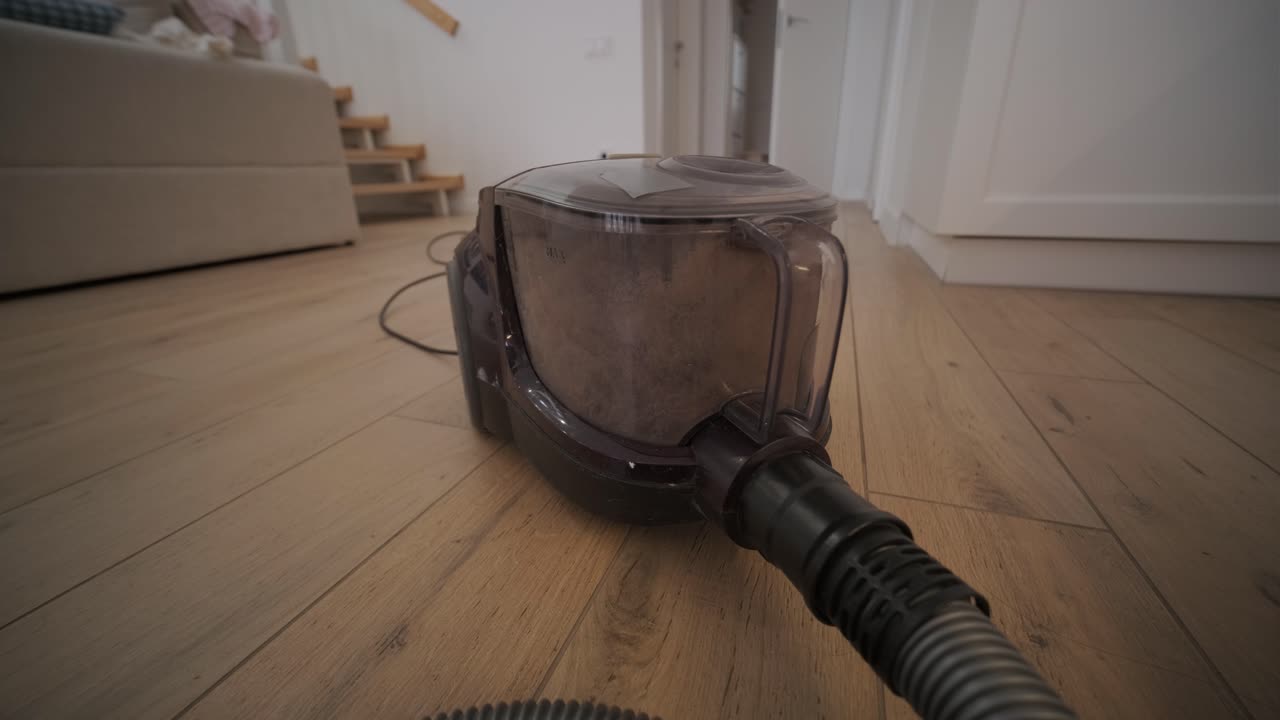 Nærbilde av en støvsuger som jobber på et tregulv
