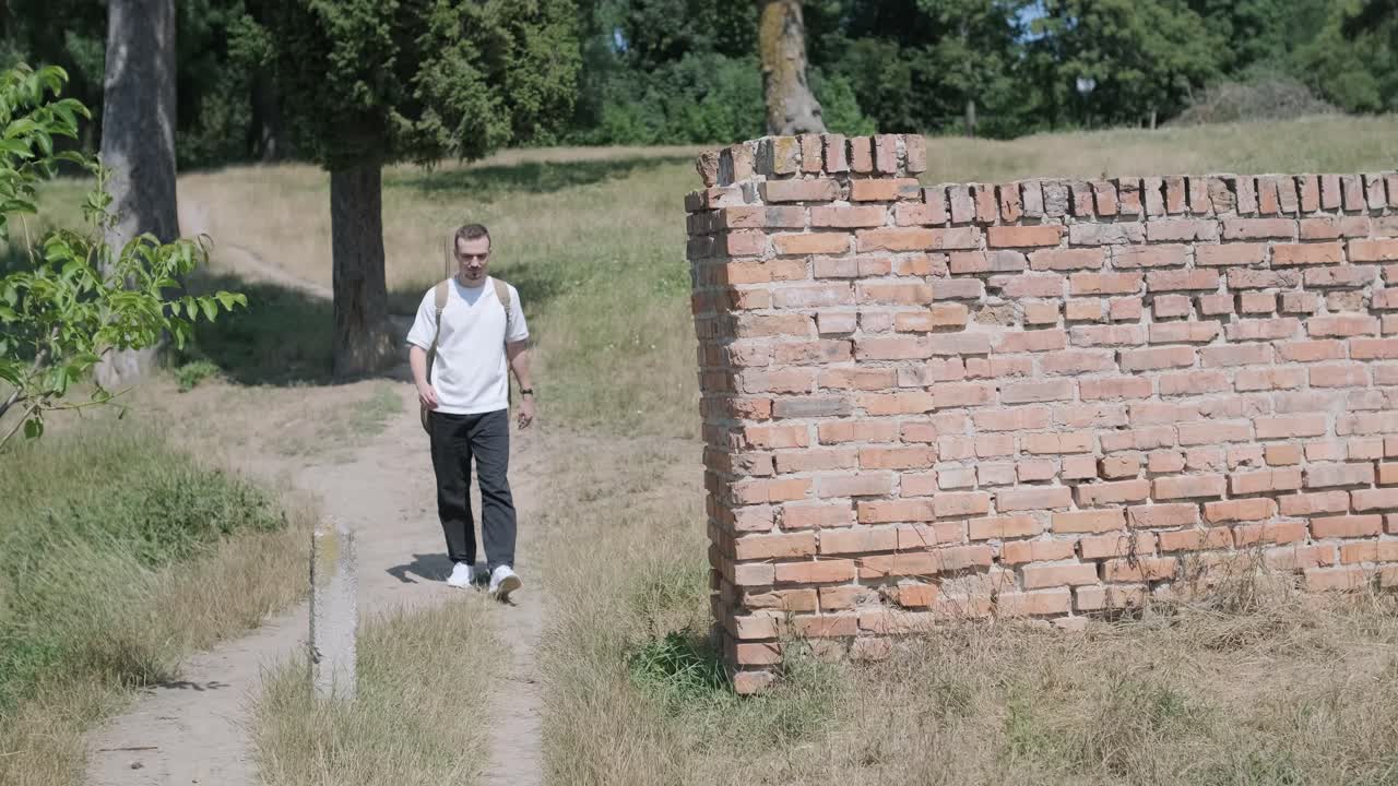joven caminando con la guitarra en la calle cerca del bosque