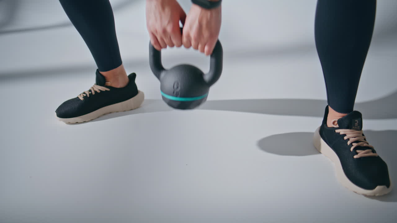 Unknown girl kettlebell squats exercises inside studio. Woman lifting weight