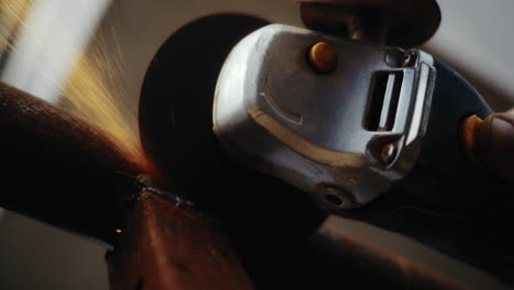 metal worker cutting old rusty tubing with angle grinder on construction site