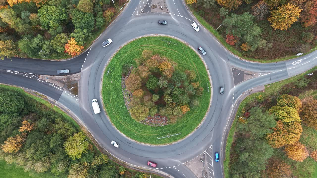 Ascending drone shot revealing a traffic roundabout with autumn colored trees