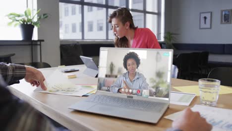 Caucasian-businessman-on-laptop-video-call-with-african-american-female-colleague-on-screen