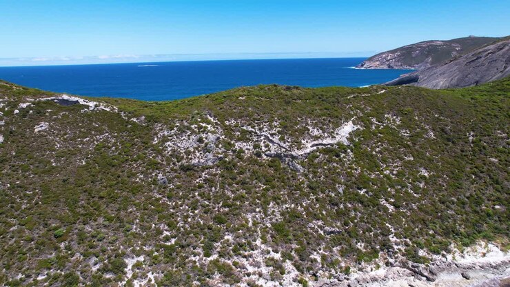 4K drone video flying over two people hiking the Bald Head Walking Trail within the Torndirrup National Park in Albany, Western Australia