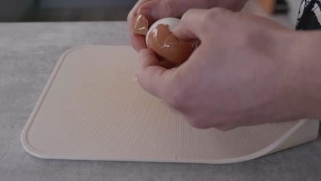 a mans hands removing the shell from some boiled eggs in a kitchen at home