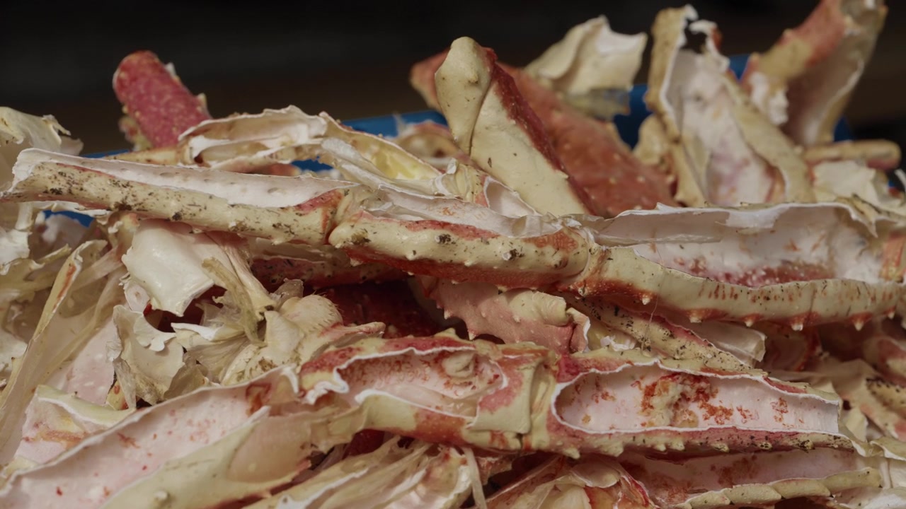 Close up of a pile of raw king crab legs with spiny shells at a fresh seafood market