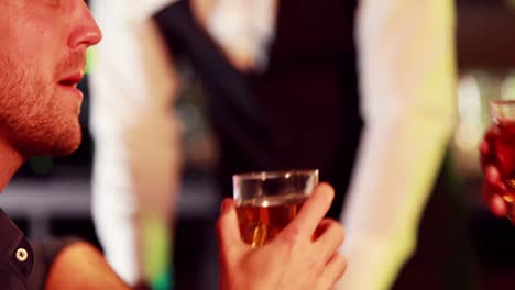 smiling friends toasting whisky glass