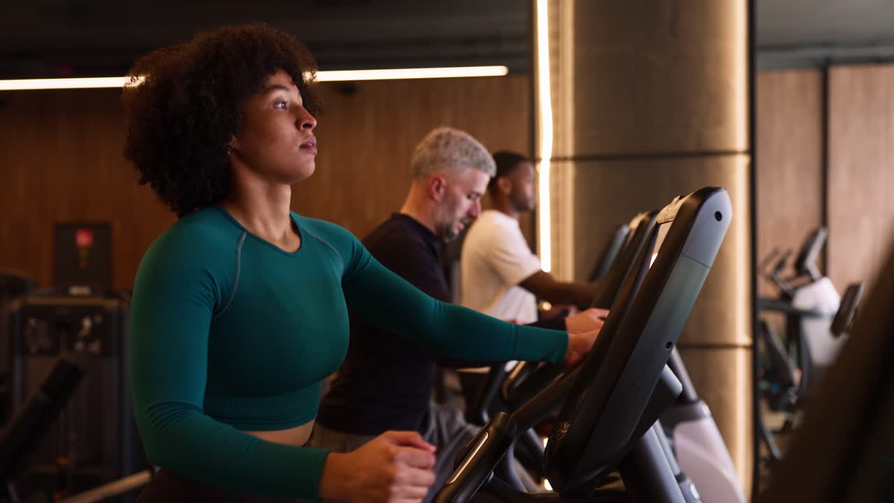 Giovane donna e uomini che si allenano sui tapis roulant in una palestra moderna.