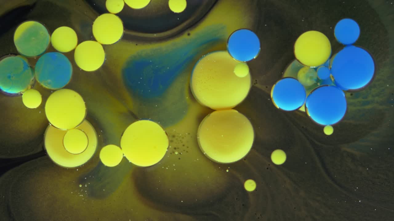 burbujas coloridas. mezcla abstracta de amarillo y azul sobre un fondo negro. fondo de pintura de color artístico.