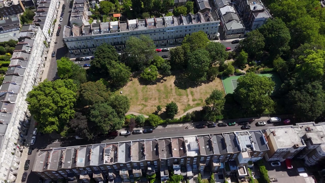 File di case d'epoca circondano una piazza giardino privata e lussureggiante con prati e sentieri di ghiaia in un quartiere residenziale di pregio