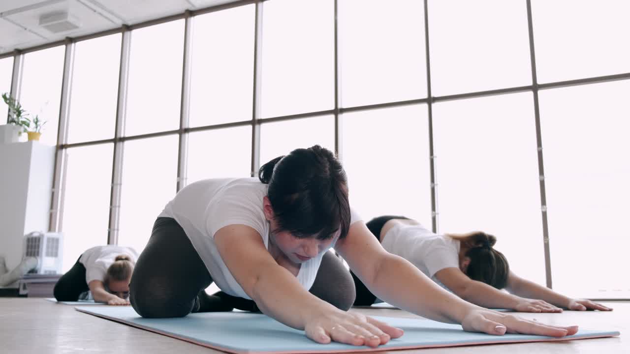 임신 한 여자 가 체육관 에서 몸 을 고 있다