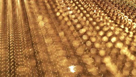 slow, smooth movement of long gold chains. uniform swing. gold background for relaxation. meditation. relax. texture for soothing. glitter. view from bottom to top. blurred