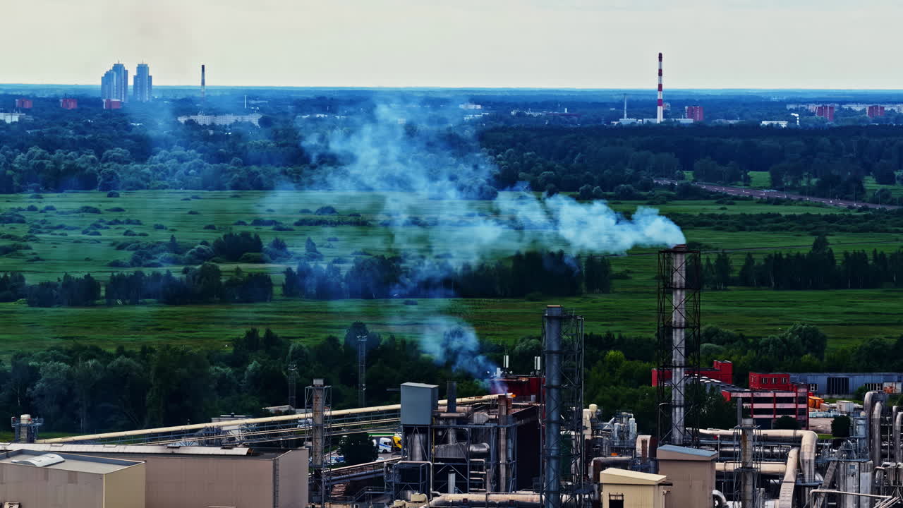 Aerial view of factory chimneys with smoke near city and green fields in Latvia
