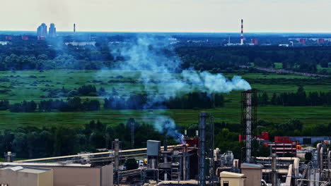 aerial view of factory chimneys with smoke near city and green fields in latvia