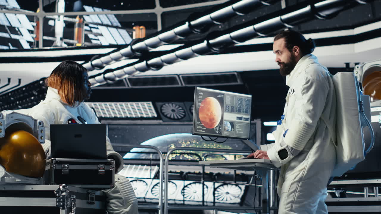 Astronaut monitoring system diagnostics on monitor, talking to colleague